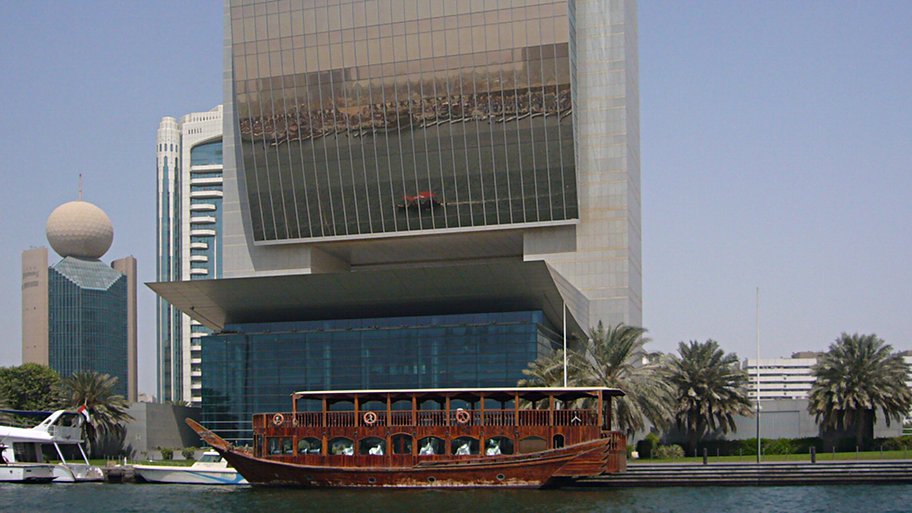 [Imbarcazione tradizionale ormeggiata sotto grattacielo nel Creek di Dubai]