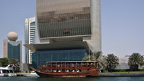 [Imbarcazione tradizionale ormeggiata sotto grattacielo nel Creek di Dubai]
