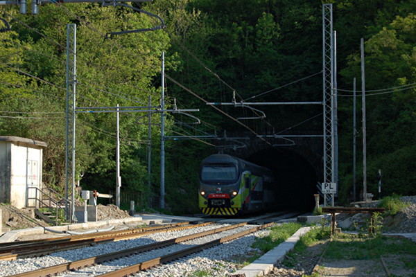 [La motrice EB 711-047 del convoglio TSR R3 054 di Trenord sbuca dalla
galleria Mombello ed attraversa il passaggio a livello di Via Cavour a
Laveno.  Il treno proviene da Gallarate (Laveno, 22 aprile
2017)]