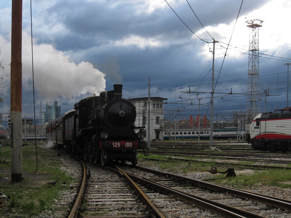[Locomotiva  a vapore  FS  625.100 entra  sul  piazzale della  Squadra
Rialzo di Milano Centrale trainando  la carrozza Corbellini di seconda
classe Bz&nbsp;38040  e la  Tipo 1921  di prima  classe Az&nbsp;10062.
Milano, 23 marzo 2014.]