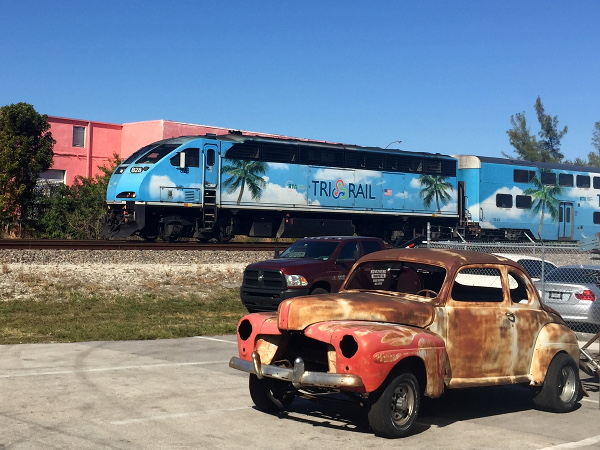 [Locomotiva  diesel-elettrica  Brookville BL36PH  n&ordm;&nbsp;828  di
Tri-Rail  in transito  tra le  stazioni di  Fort Lauderdale  Airport e
Sheridan Street.  In  primo piano il relitto di una  Ford 1947.  Dania
Beach, 11 gennaio 2019.]